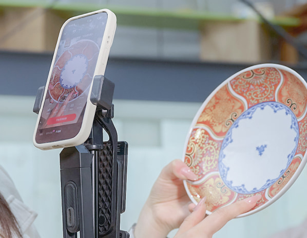 陶磁器をスマートフォンで撮影し、SNSやライブコマースを通じて価値と魅力を発信する販売プロモーションの様子