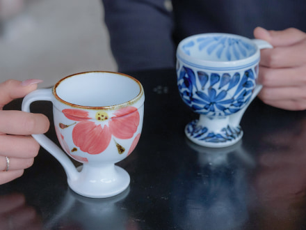 繊細な絵柄のコーヒーカップを手に取り、日本の器がもたらす心満たされるひとときを共有する二人の様子